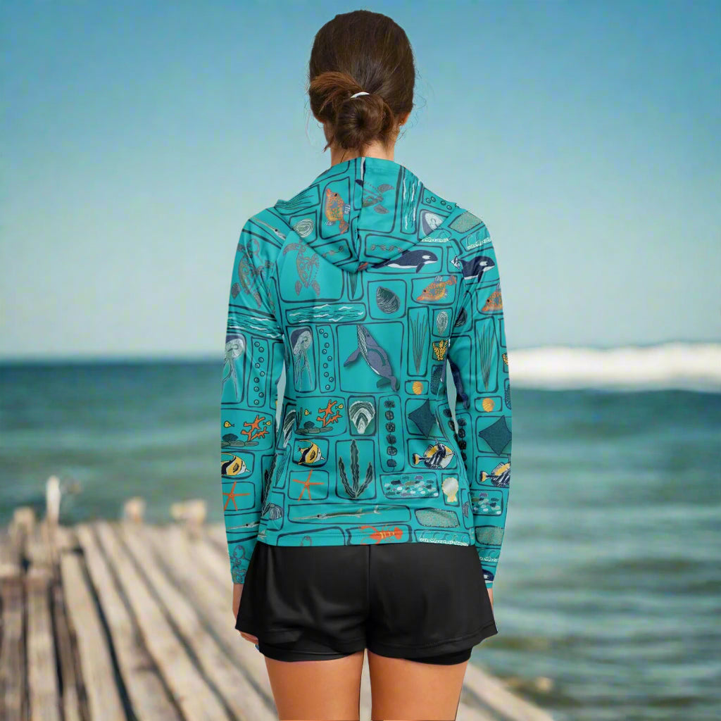Lady wearing a teal sun hoodie with under water sealife design